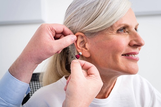 Frau bekommt von Hörakustiker ein modernes Hörgerät zur Verbesserung des Hörvermögens eingesetzt.